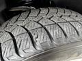 Close-up of a textured tire from a 2014 Ford F-150 showing deep treads and small metal studs for grip