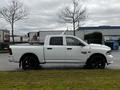 A white 2022 RAM 1500 Classic pickup truck with a crew cab and black wheels parked on grass