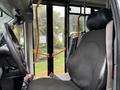 A 2020 Chevrolet Express vehicle interior showing the driver's seat and steering wheel with a bus-style door and handrails visible in the background