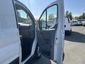 A 2016 Ford Transit with its front driver side door open displaying the interior features and seating layout
