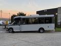 A 2019 Chevrolet Express shuttle bus with large windows and a grey exterior parked on a driveway