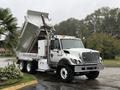 A white 2011 International 7500 dump truck with an elevated bed for unloading cargo is parked on a roadway