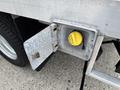 A metallic access panel with a yellow cap is open on the side of a 2015 Ford F-350 SD revealing part of the truck's fuel or fluid system