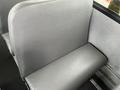 A gray vinyl bus seat with a smooth texture and simple design positioned in a vehicle interior