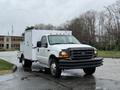 A white 2000 Ford F-450 truck with a service body and front bumper protection