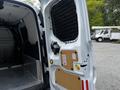 A 2016 Ford Transit Connect with an open side door revealing a metal grate and a mounted device on a wooden panel inside the cargo area