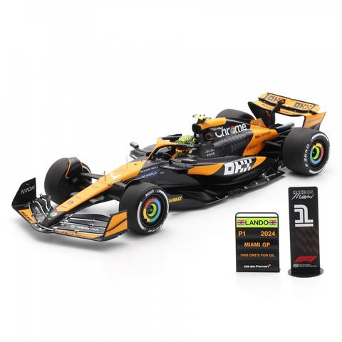 A detailed model car of a Spark McLaren MCL38 featuring a vibrant orange and black design with driver #4 L. Norris on the side accompanied by pit boards for the 2024 Miami Grand Prix