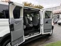 A 2018 Ford Transit with open front doors revealing a spacious interior featuring grey seats and a minimalistic design
