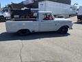 A 1962 Ford F-100 pickup truck with a sleek gray exterior, lowered stance, and black wheels parked on a paved surface