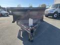 A 2024 Southland 18 Foot Dump Trailer with a black body and a metal bed is parked with a hitch visible at the front