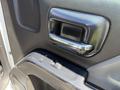 Close-up of the door handle and window controls of a 2016 GMC Sierra 1500 with a black textured interior and chrome accents