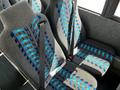 Two bus seats with gray fabric and blue patterned stripes, featuring seatbelts on each seat
