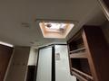 Inside view of a 2013 Outdoor Wind River with a ceiling vent and a sliding shower door, showcasing cabinetry and wall-mounted hooks