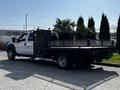 A 2016 Ford F-550 flatbed truck with a black metal bed and toolboxes mounted on the sides