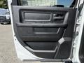 The interior door panel of a 2022 RAM 5500 featuring a black handle, armrest, speaker grille and textured surface