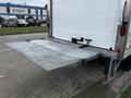 A silver 2018 Isuzu NRR with a flat loading ramp extended from the back for easy access to the cargo area