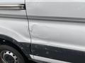 A 2018 Ford Transit van with a dent on the side door and visible scratches, covered in water droplets