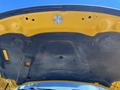 The underside of a yellow hood of a 2015 RAM 1500 truck showing the smooth surface with mounting points and a few small indentations