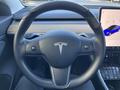 The steering wheel of a 2019 Tesla Model 3 featuring a minimalist design and the Tesla logo in the center