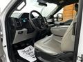 Interior of a 2016 Ford F-150 featuring a light gray leather driver's seat and dashboard with various control buttons and a digital display
