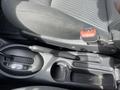 Close-up of the gear shift and center console of a 2005 Chrysler PT Cruiser featuring a black fabric seat and a red seatbelt latch