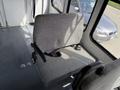 A grey upholstered seat inside a 2010 Ford Econoline with armrests and seatbelt visible
