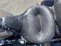 A black motorcycle seat with visible wear and patches of duct tape and decorative studs