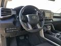 Interior view of a 2023 Toyota Tundra featuring a steering wheel with controls a digital dashboard and a touchscreen display on the console
