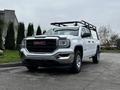 A white 2018 GMC Sierra 1500 pickup truck with a black roof rack and chrome accents parked on a concrete surface