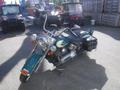 A teal and silver 2009 Harley-Davidson FLSTC motorcycle with a classic design featuring a large front headlight and saddlebags