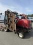 A red 2013 Toro Grounds Master 5910 lawn mower with a raised cutting deck showing its blades and mounted on large wheels for terrain navigation