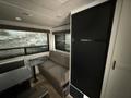 Interior view of a 2022 Keystone Hideout RDWE 20RDWE featuring a sofa and a table with a compact refrigerator to the side