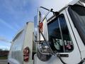 A 2010 Autocar Xpeditor garbage truck with a shiny side mirror and a bright orange light attached to the driver's side