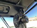 A black mechanical fan mounted on the ceiling of a vehicle cabin with visible wiring and a textured surface