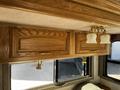 A 2000 Ford Motorhome interior featuring wooden cabinetry with two upper cabinets and a light fixture with three glass shades
