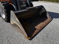 A rusted metal bucket attachment from a 2017 Gehl R105 skid steer loader with visible wear and distinct mounting points