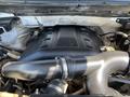 A 2014 Ford F-150 engine featuring a large black engine cover with the number 5.0 and visible components such as hoses and pipes