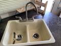 A double basin kitchen sink with a chrome faucet featuring two handles and items like pens and a sponge inside the sink