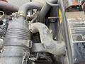 A close-up view of the engine components of a 2015 Kubota F3990 featuring various hoses and a metal clamp system