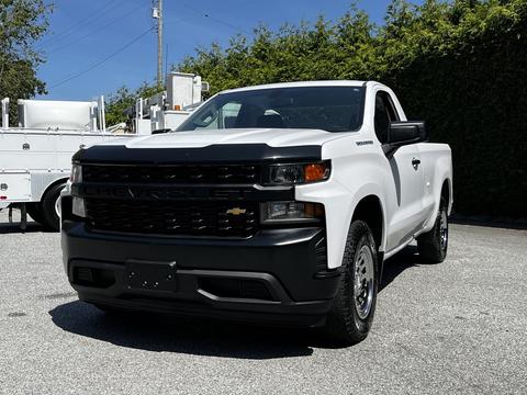 A white 2021 Chevrolet Silverado with a black grille and aggressive front design parked with no visible license plate