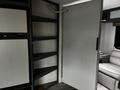 Interior view of a 2022 Aspen Trail camper showing shelves a door and part of a seating area