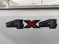 A close-up view of a 4x4 badge on a 2017 Ford F-250 SD with raindrops on the surface