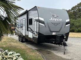 A 2021 Jayco Jay Flight travel trailer with a sleek gray exterior featuring the Jayco logo prominently displayed on the front and a hitch attached to the front tongue