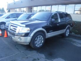 A black and silver 2008 Ford Expedition parked with chrome wheels and a roof rack