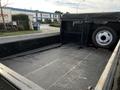 A 2021 Ford F-550 flatbed truck with a black rubberized bed liner and a spare tire mounted on the side