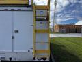 A white 2008 Ford F-550 with a yellow ladder on the side and a silver step leading up to the roof access