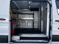 A 2018 Ford Transit cargo van with open back doors revealing metal shelving and a rubber floor mat inside