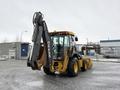 A 2011 John Deere 310SJ 4x4 Wheel Loader with an extended hoe attachment and a 4 in 1 bucket is positioned with its back facing the viewer