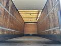 Interior of a 2015 Freightliner M2 106 box truck with wooden walls and a flat floor featuring metal latch strips along the sides