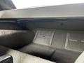 Interior storage compartment of a 1992 Chevrolet Corvette featuring gray fabric lining and metal clips for securing items